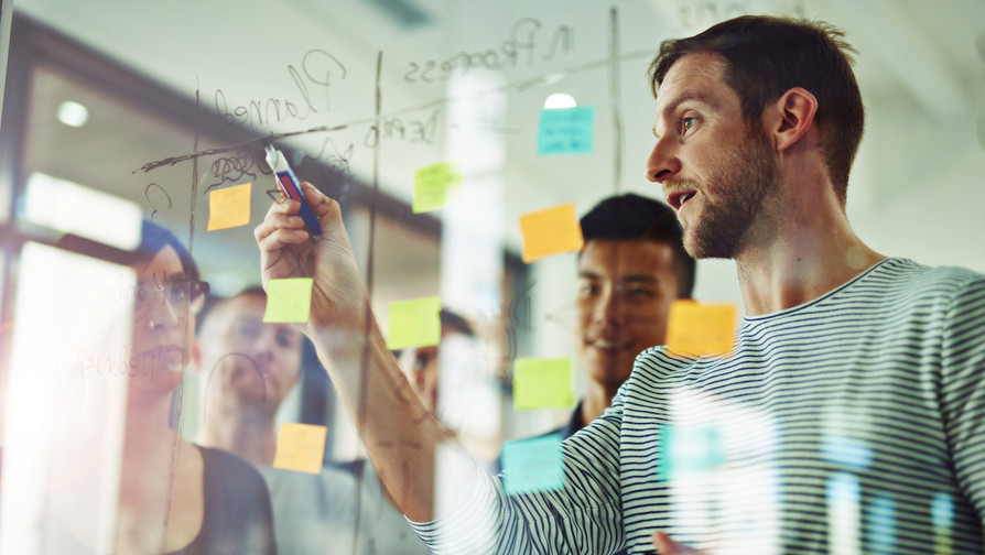 Mann vor Projektplanungstafel mit Post-ITs