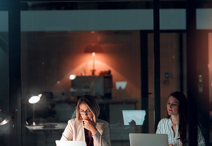 Zwei Frauen abends im Büro am Schreibtisch