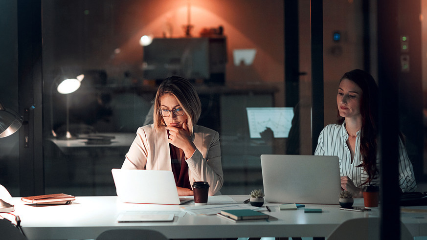 Zwei Frauen abends im Büro am Schreibtisch