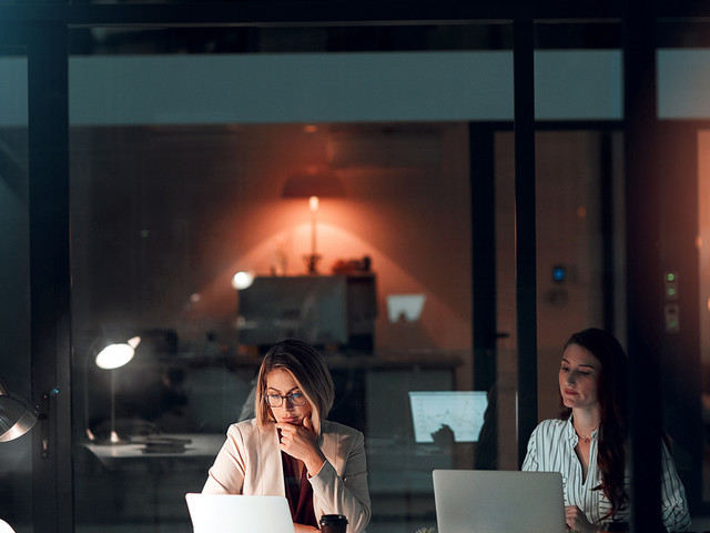 Zwei Frauen abends im Büro am Schreibtisch