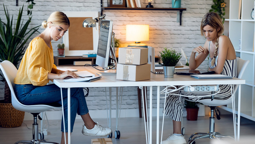 Zwei Frauen arbeiten in einer Agentur am Schreibtisch