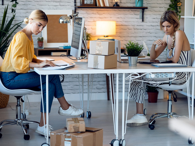 Zwei Frauen arbeiten in einer Agentur am Schreibtisch